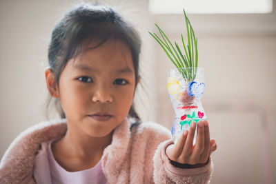 Portrait of cute girl holding plant in container