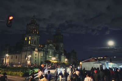 Crowd at illuminated city against sky at night