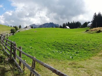 Scenic view of grassy field against cloudy sky