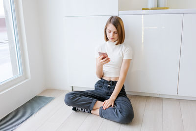 Portrait of young woman sitting on hardwood floor at home