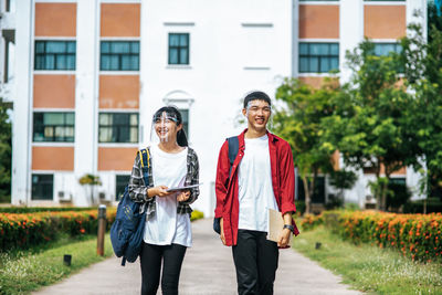 Portrait of smiling young woman standing against building