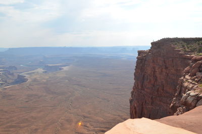 Lone figure overlooks the white rim and green river in canyonlands national park island in the sky