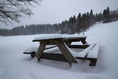 Snow covered field by trees against sky