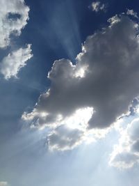 Low angle view of sunlight streaming through clouds