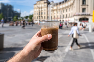Cropped image of hand holding glass of city