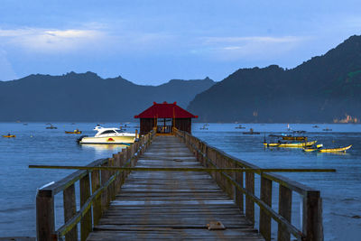 A photo of a scenic wooden pier with a boat docked at the end in trenggalek, east java, indonesia.