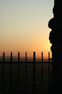 Silhouette railing by sea against clear sky during sunset