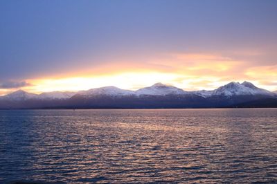 Scenic view of lake and snowcapped mountains against sky during sunset