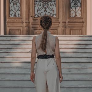 Rear view of woman standing against staircase