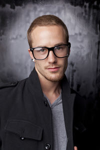 Portrait of young man standing against wall