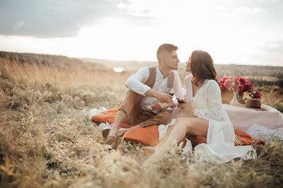 Couple sitting on land against sky