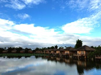 Houses by lake against blue sky