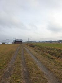 Road amidst field against sky