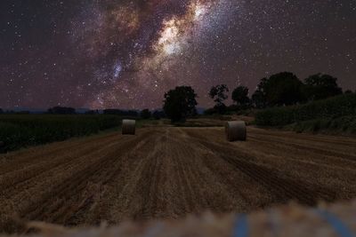 Hay bales on field against sky at night