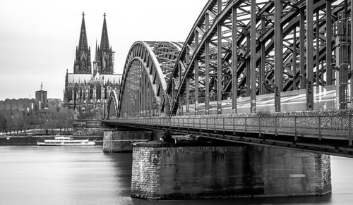 Bridge over river by buildings against sky in city