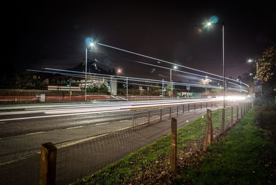 Light trails on road against sky at night