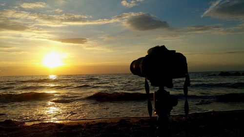 Scenic view of sea at sunset with camera on tripod