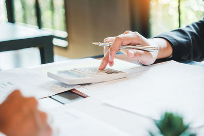 Midsection of man holding paper on table