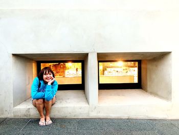 Full length of woman standing against building wall