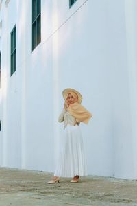 Woman with umbrella standing against building