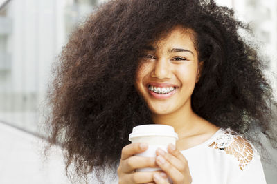 Portrait of smiling teenage girl with disposable cup