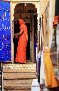 Woman wearing orange sari standing at jewelry store