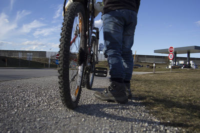 Low section of man on road against sky