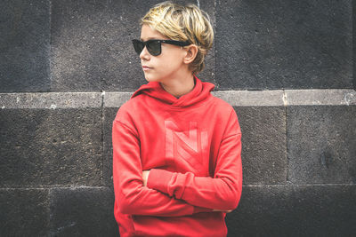 Boy wearing sunglasses while standing against wall
