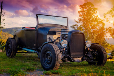 Vintage car parked at grassy area against cloudy sky