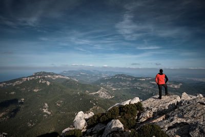 Rear view of man standing on mountain against sky