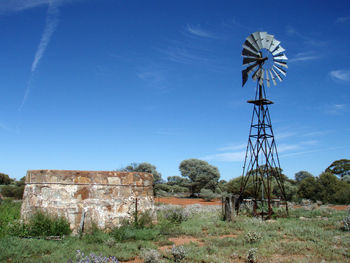 Low angle view of windmill on field against sky