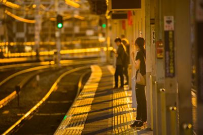 People standing on railroad station at night