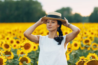 Portrait of woman wearing hat while standing against yellow flower