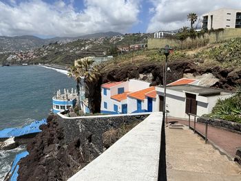 Buildings by sea against sky