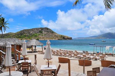 Chairs and tables on beach against sky