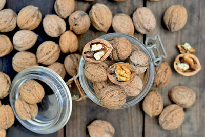 Top view on shelled walnuts in a glass jar among others on wooden table