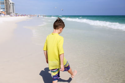 Rear view of boy walking at beach