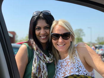 Portrait of smiling women against sky seen through car window