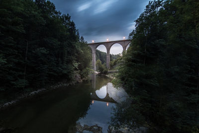 Arch bridge over river against sky