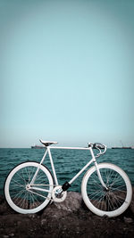 Bicycle parked at harbor against clear sky