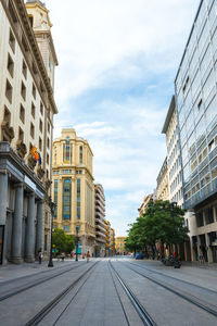 Road amidst buildings in city against sky