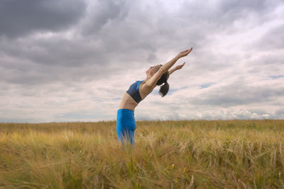 Woman exercising and doing a stretch in the middle of a field. workout outdoors.