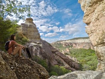 Woman looking at cliff against sky