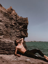 Woman on rock at beach against sky