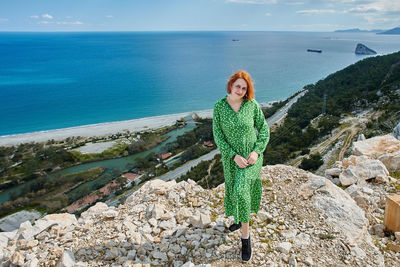 Portrait of woman standing on rock by sea against sky