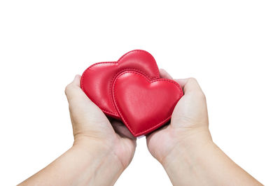 Close-up of hand holding heart shape against white background