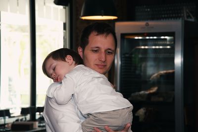 Father standing in a restaurant holding his little toddler who fel asleep