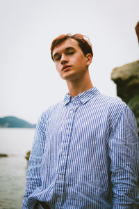 Young man standing against sea