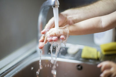 Close-up of woman hand with faucet in water