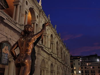 Low angle view of statue against illuminated buildings in city